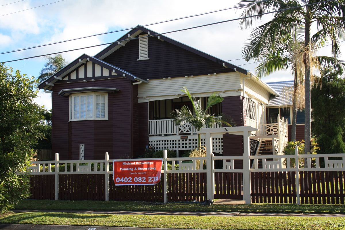 Heritage-listed Queenslander in Enoggera painted in deep burgundy with cream trim, Michael's red sign on the fence