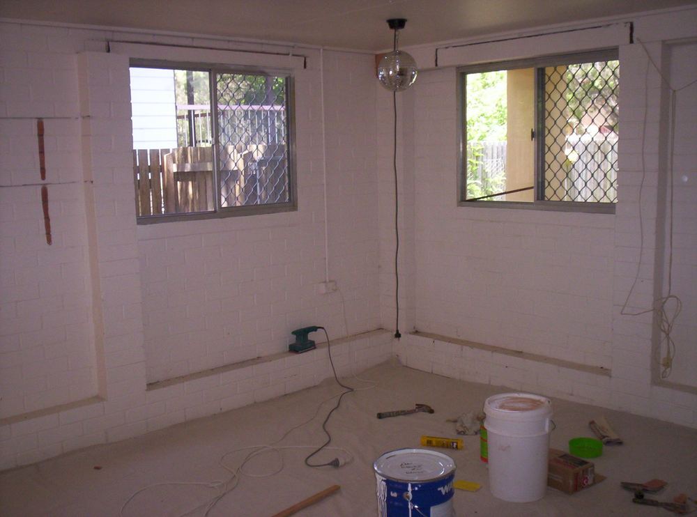 Lawnton rumpus room mid-preparation, bare white brick walls and paint tins on the floor