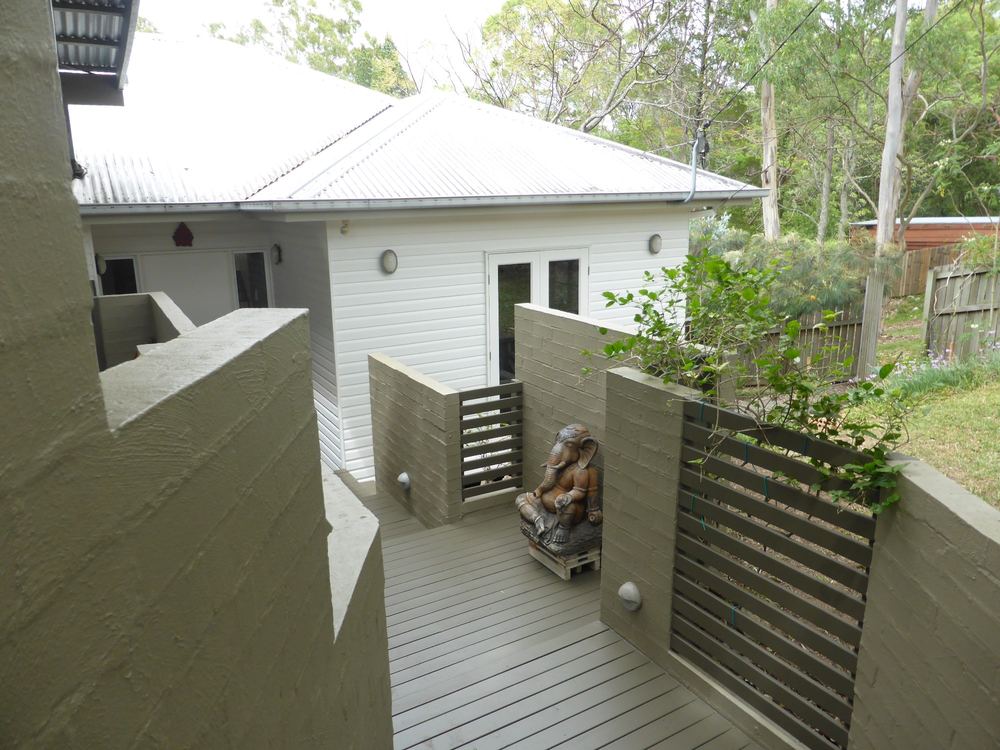 Taringa house front entry with grey rendered walls and timber slat screens